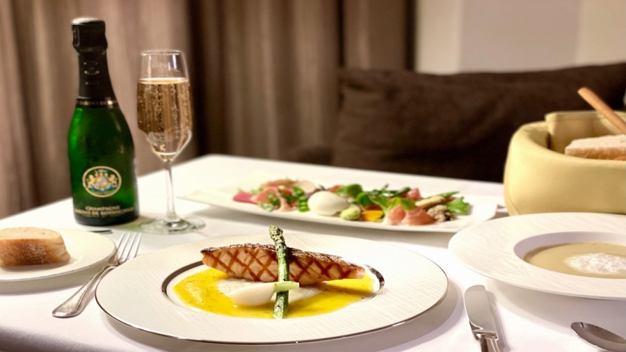 A scene of dinner enjoyed via in-room dining, featuring an array of meat-based main courses.