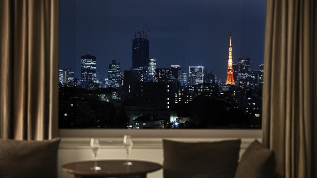 From the window of the hotel room, Tokyo Tower is visible, and two wine glasses are lined up on the table.